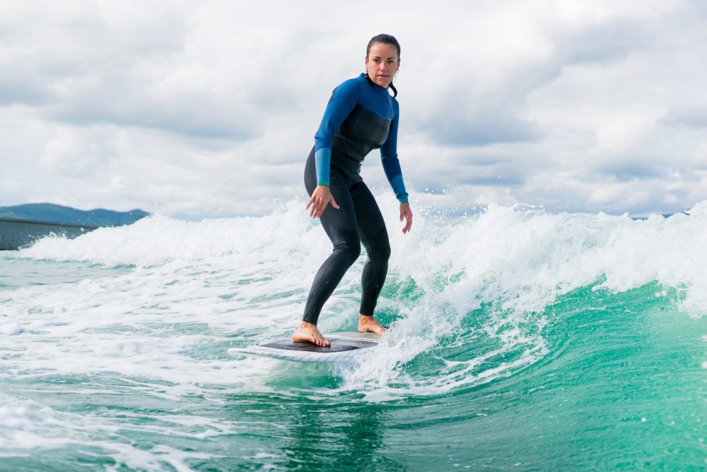 Athletic woman in wetsuit riding a board across the water behind boat. Wakeboarding concept